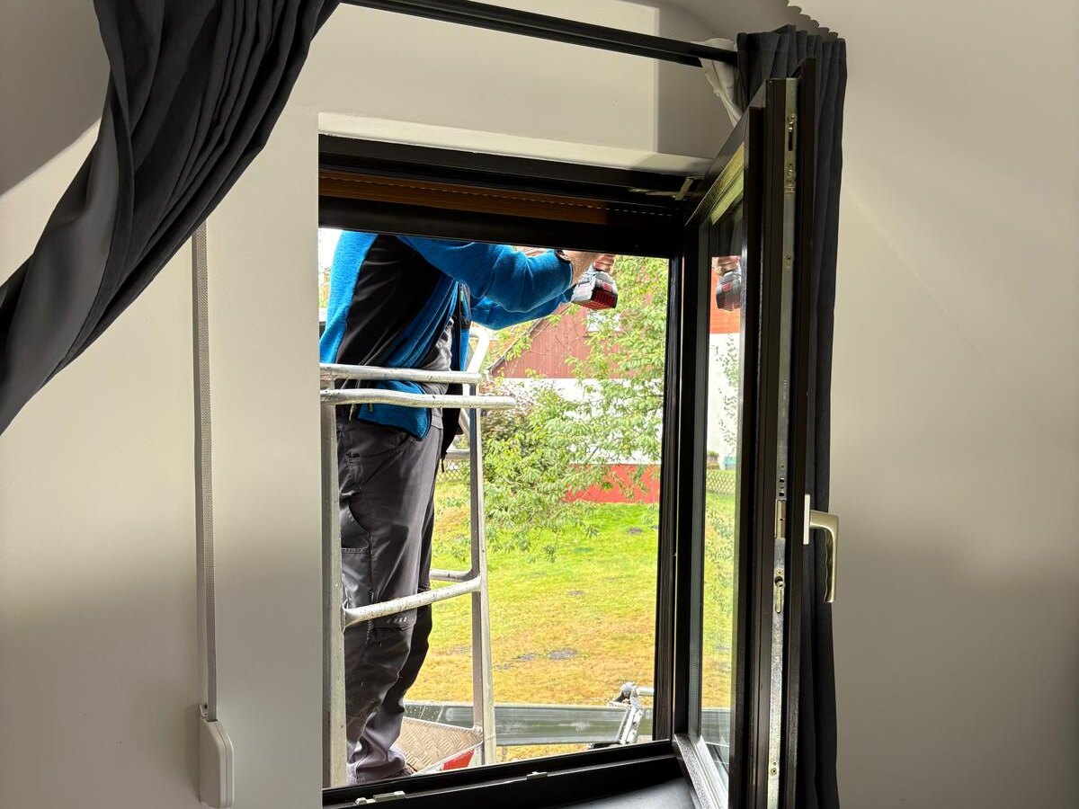Blick aus einem Zimmer durch das geöffnete Fenster auf den Arbeitskorb vor der Fassade
