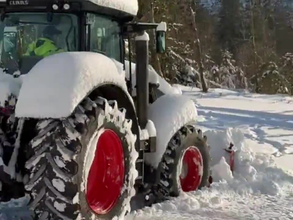 Winterdienst von GrünWerk Harz: Traktor schiebt Schnee auf einer verschneiten Zufahrt im Oberharz